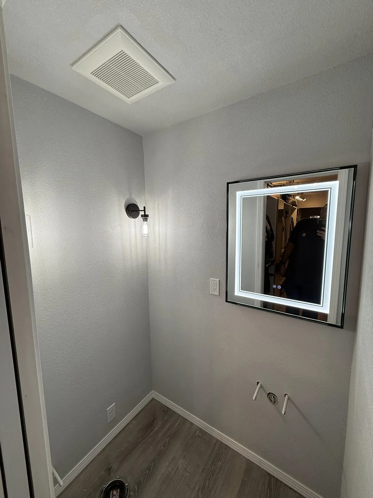 Bathroom with a backlit LED mirror, wall sconce and ceiling exhaust fan