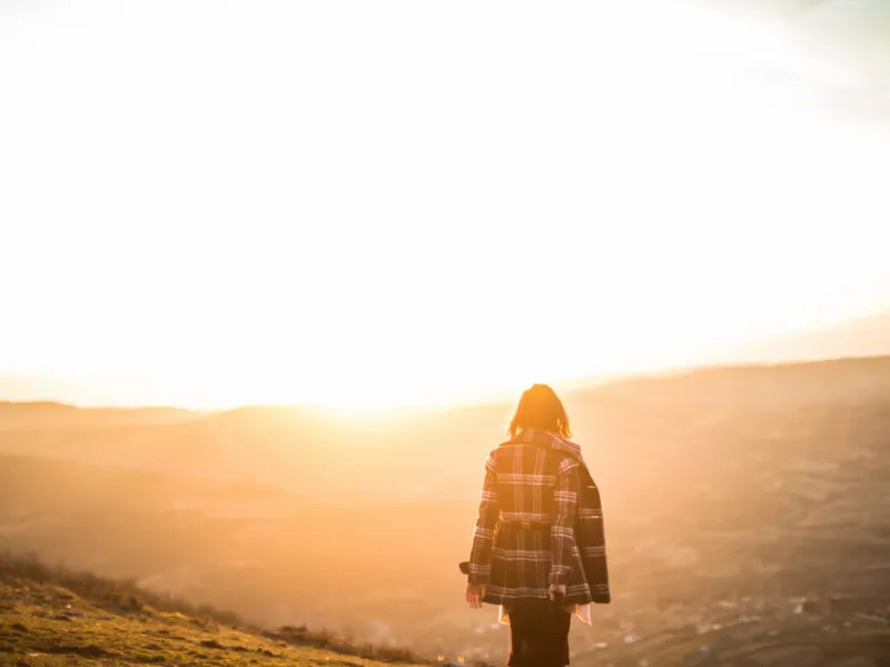 woman with her back to camera on a hill looking at the sunrise