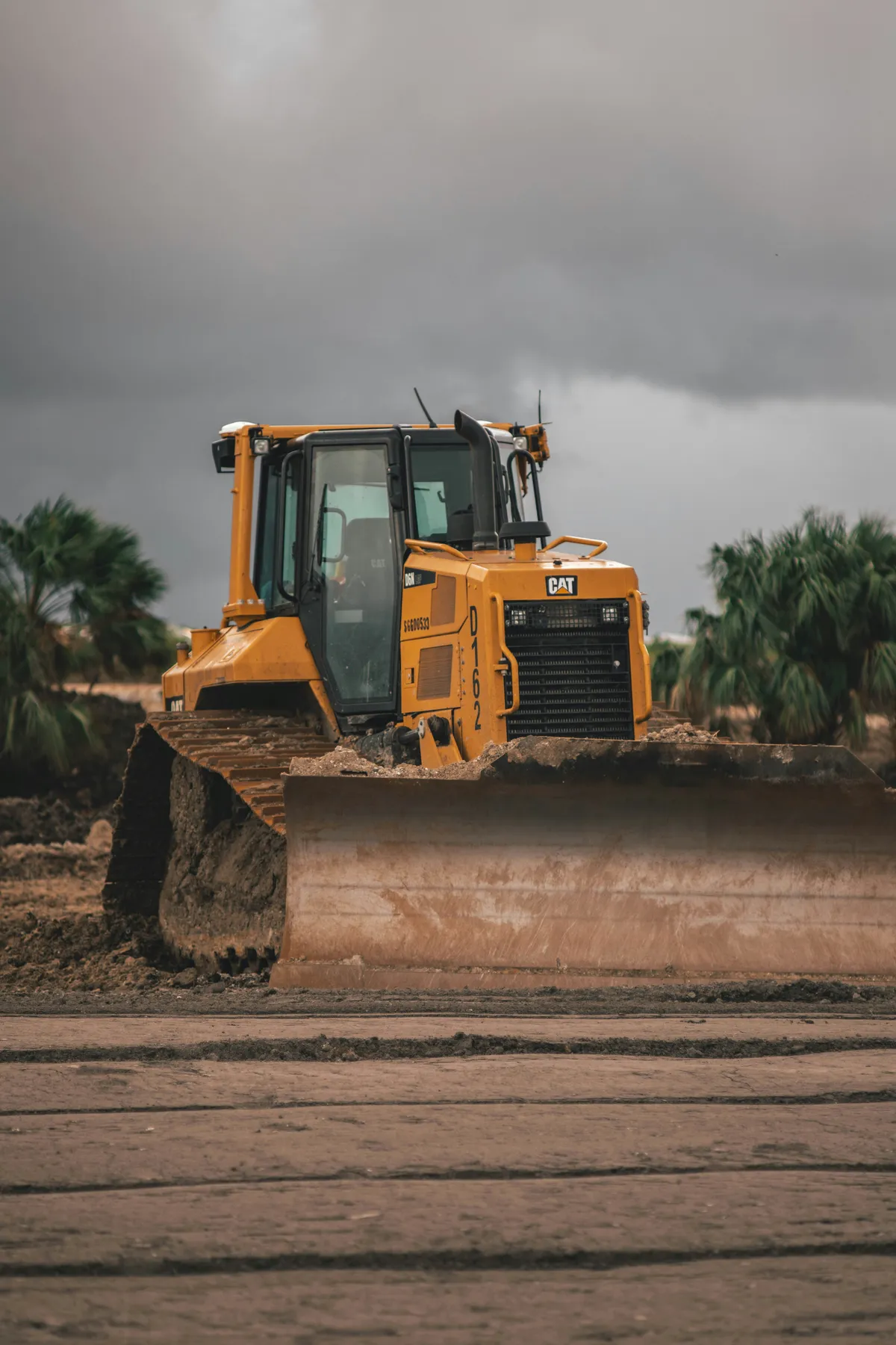 Tracked bulldozer with its blade lowered on exposed earth.