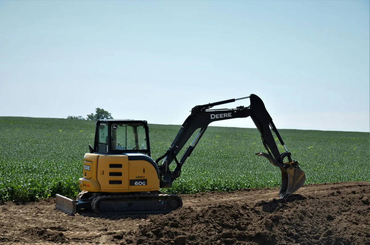 Compact tracked excavator working beside an exposed earth cut.