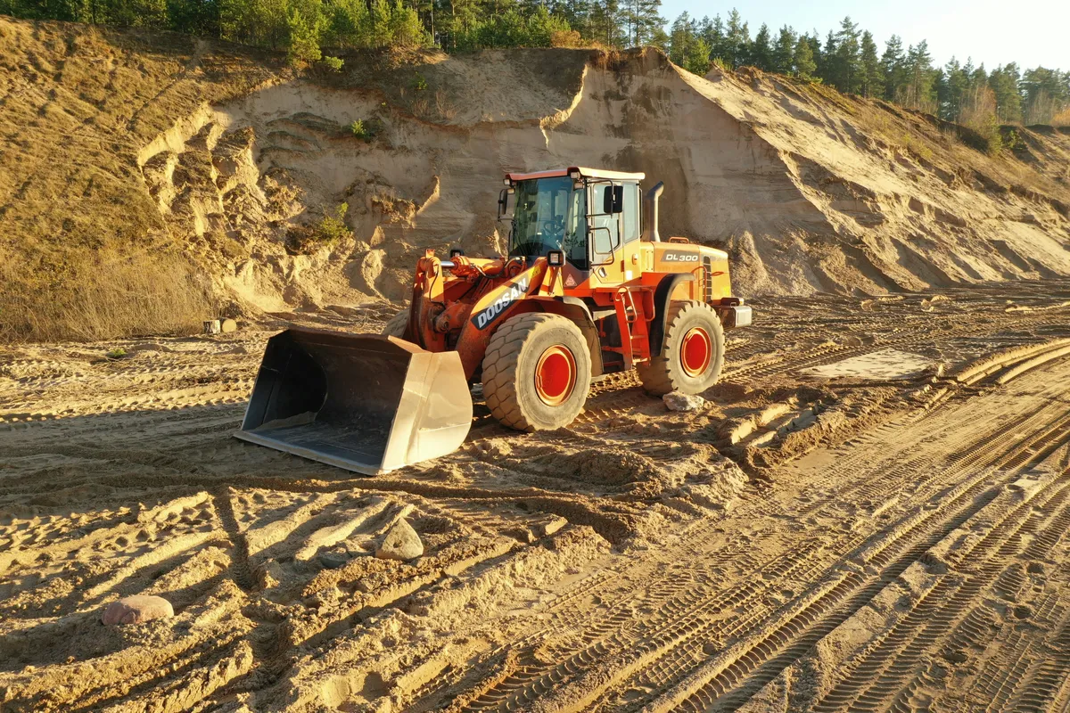Wheel loader with its front bucket lowered on a graded earthwork site.