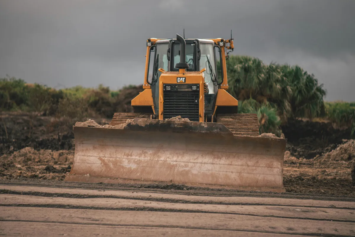 Tracked bulldozer facing forward with its blade lowered across a graded earthwork area.
