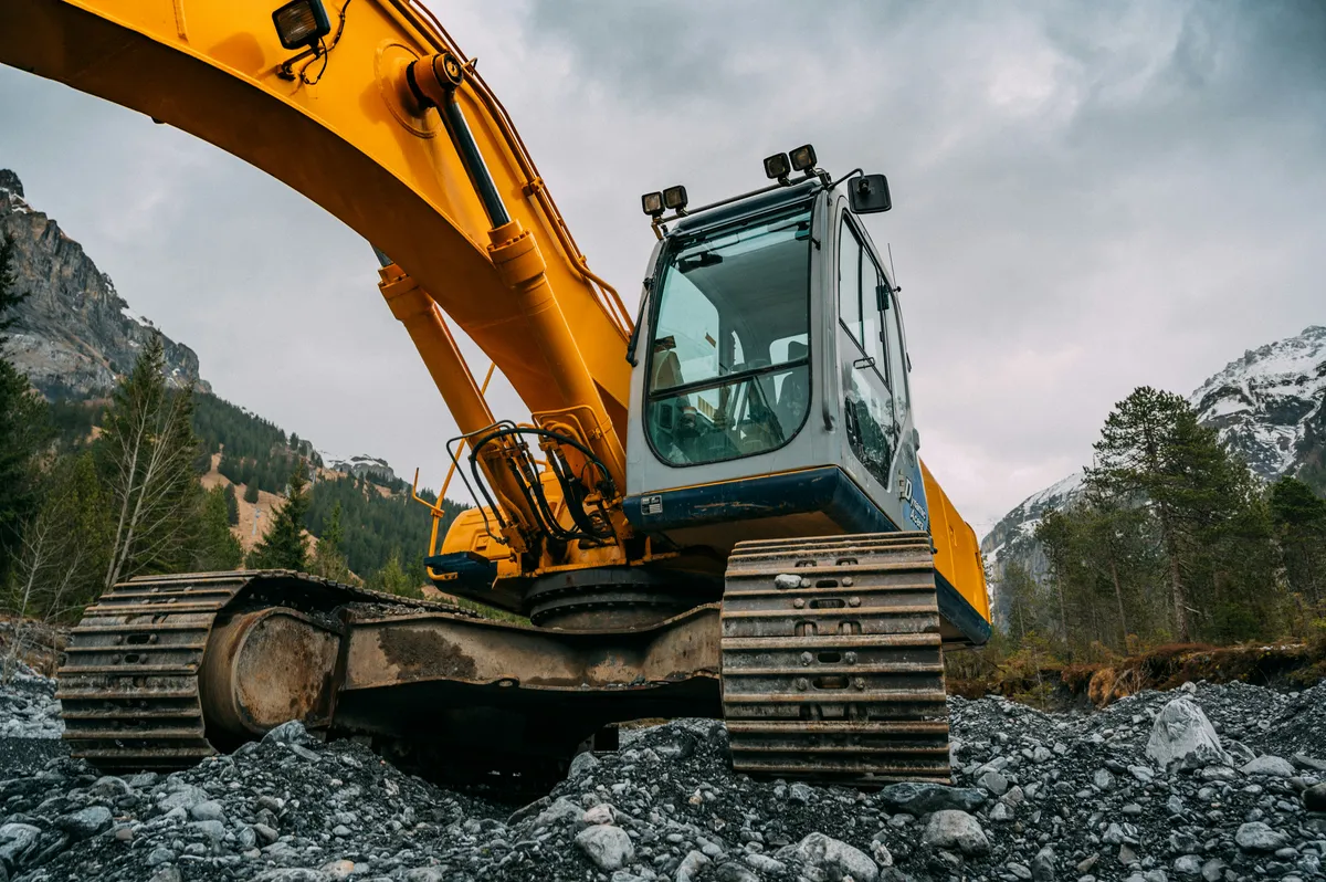 Excavator cab, tracked undercarriage and boom viewed from ground level.
