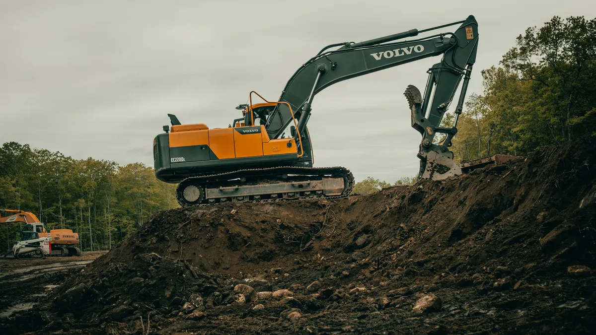 Tracked excavator standing beside a cut in exposed earth.