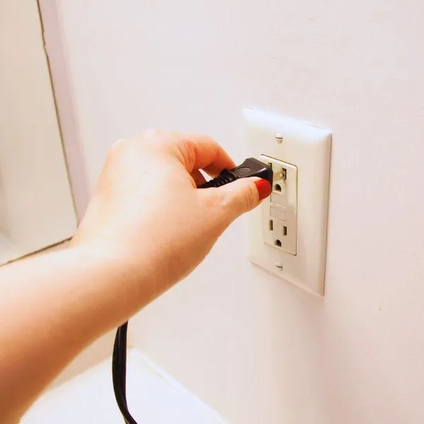 Woman unplugging electronics to reduce EMF exposure at home