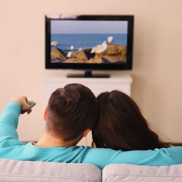 A couple watching TV at a distance to reduce EMF exposure at home