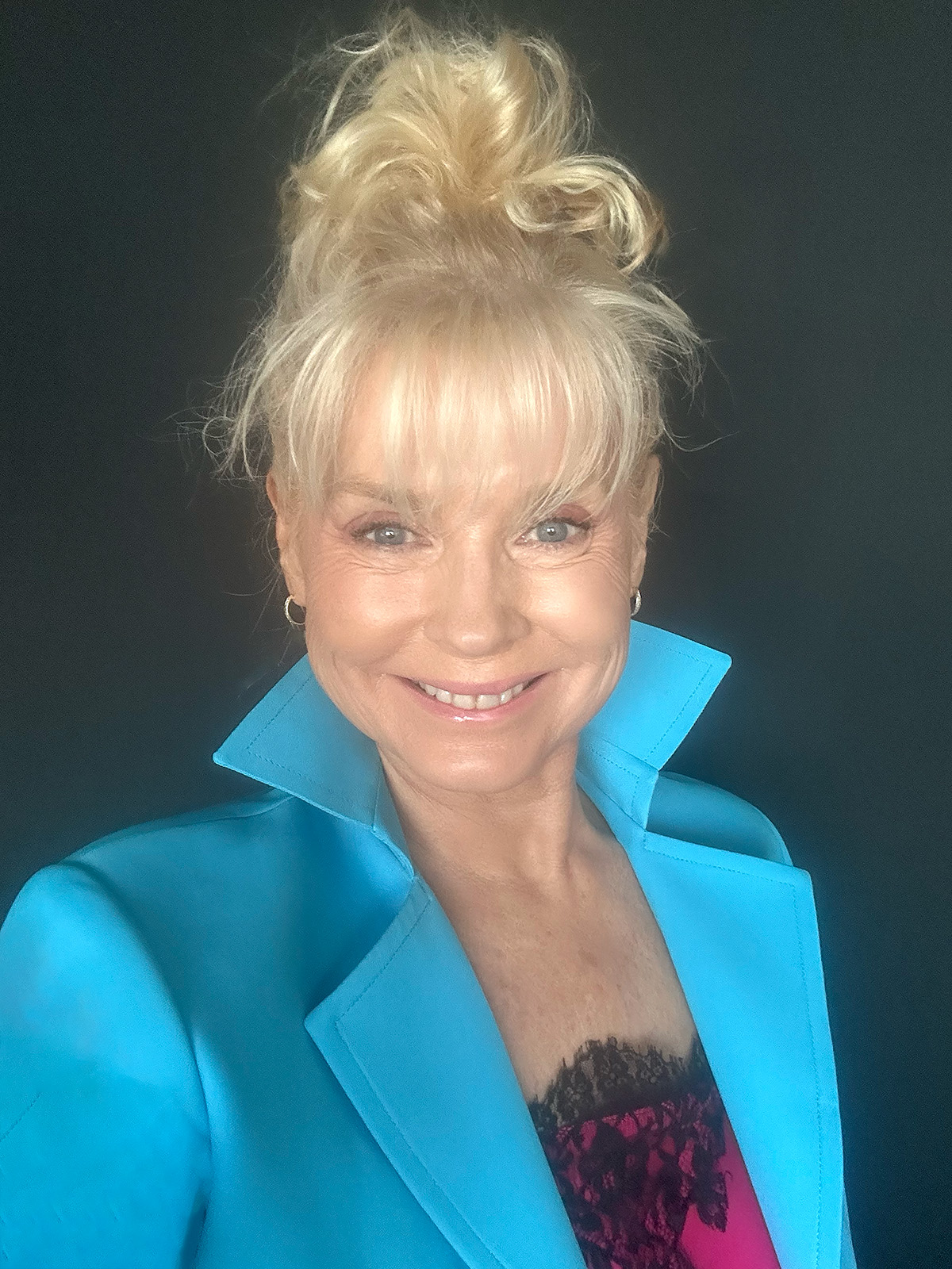 Experienced coach, mid-40s, sitting at a desk with open notebook and laptop, warmly engaging in a virtual session. The background features bookshelves and certificates, emphasizing credibility and approachability.