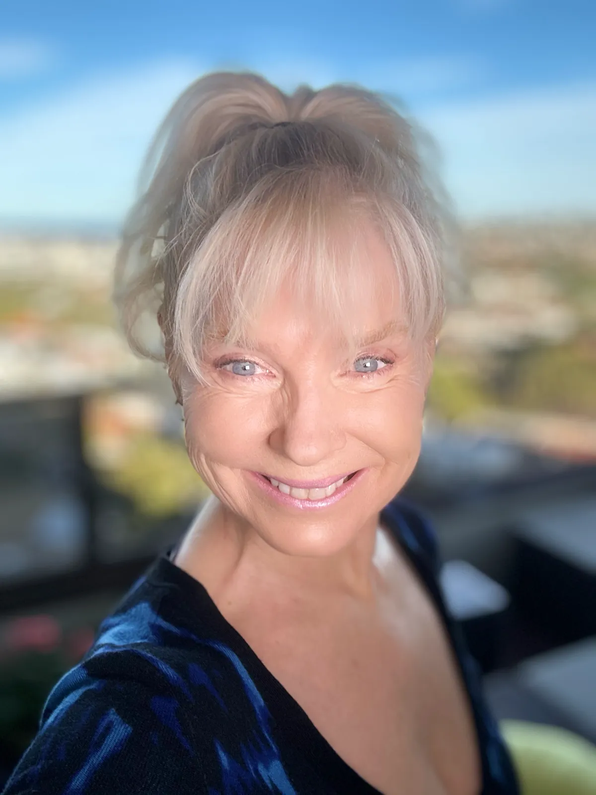 Experienced coach, mid-40s, sitting at a desk with open notebook and laptop, warmly engaging in a virtual session. The background features bookshelves and certificates, emphasizing credibility and approachability.