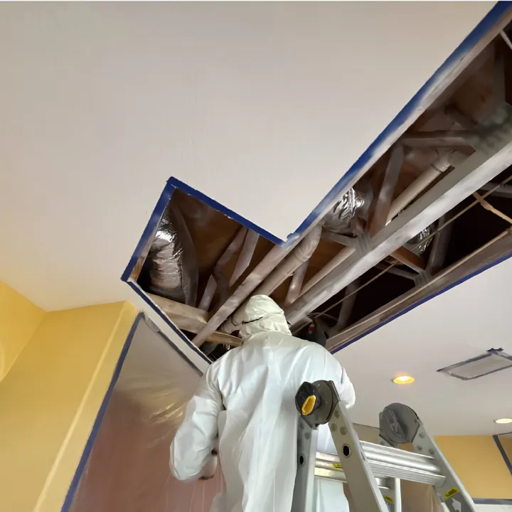 Restoration technician checking a ceiling for hidden moisture damage