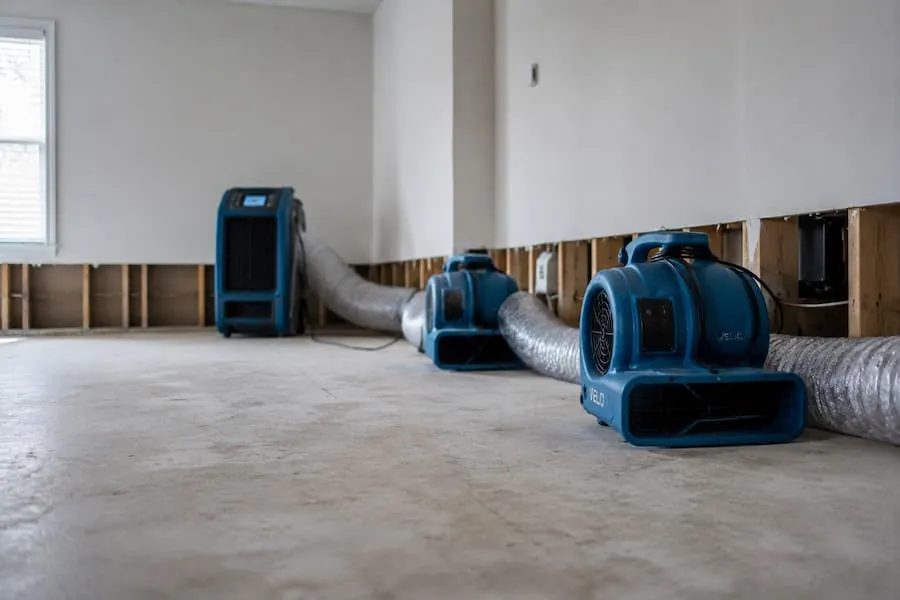 Air movers and a dehumidifier drying an empty room after water damage