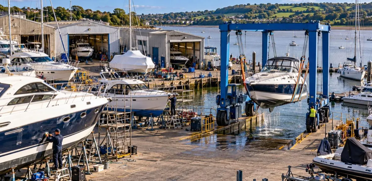 Boats on cradles in a UK storage yard beside a travel lift, the risks covered by boat yard insurance