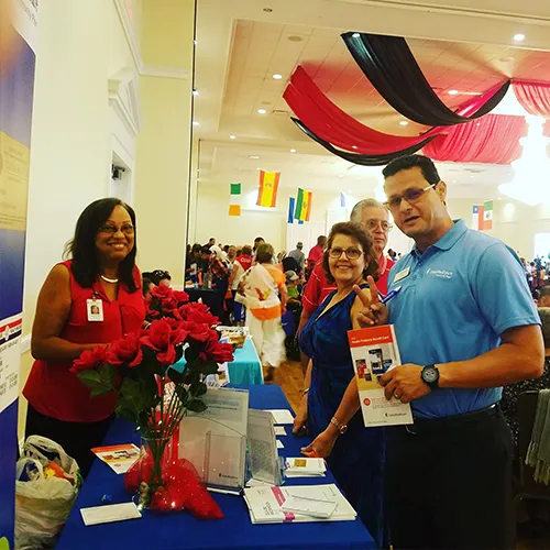 photo of luis daza at an event talking to a lady at the booth