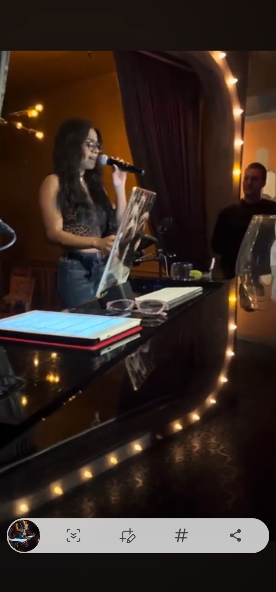 Close-up black and white photo of a professional recording microphone with a sound screen in a studio setting.