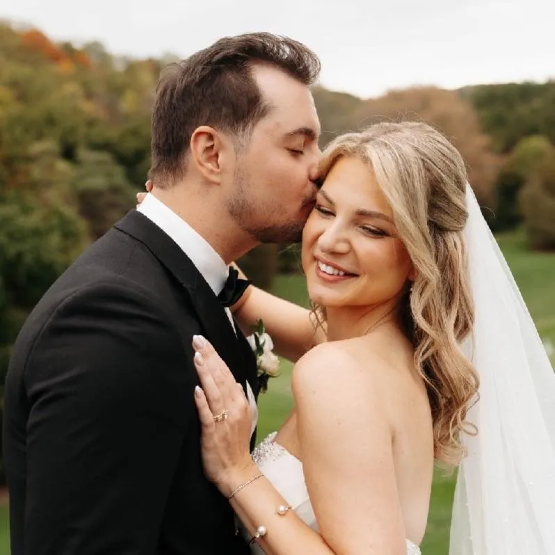 Wedding portrait of groom kissing bide's temple