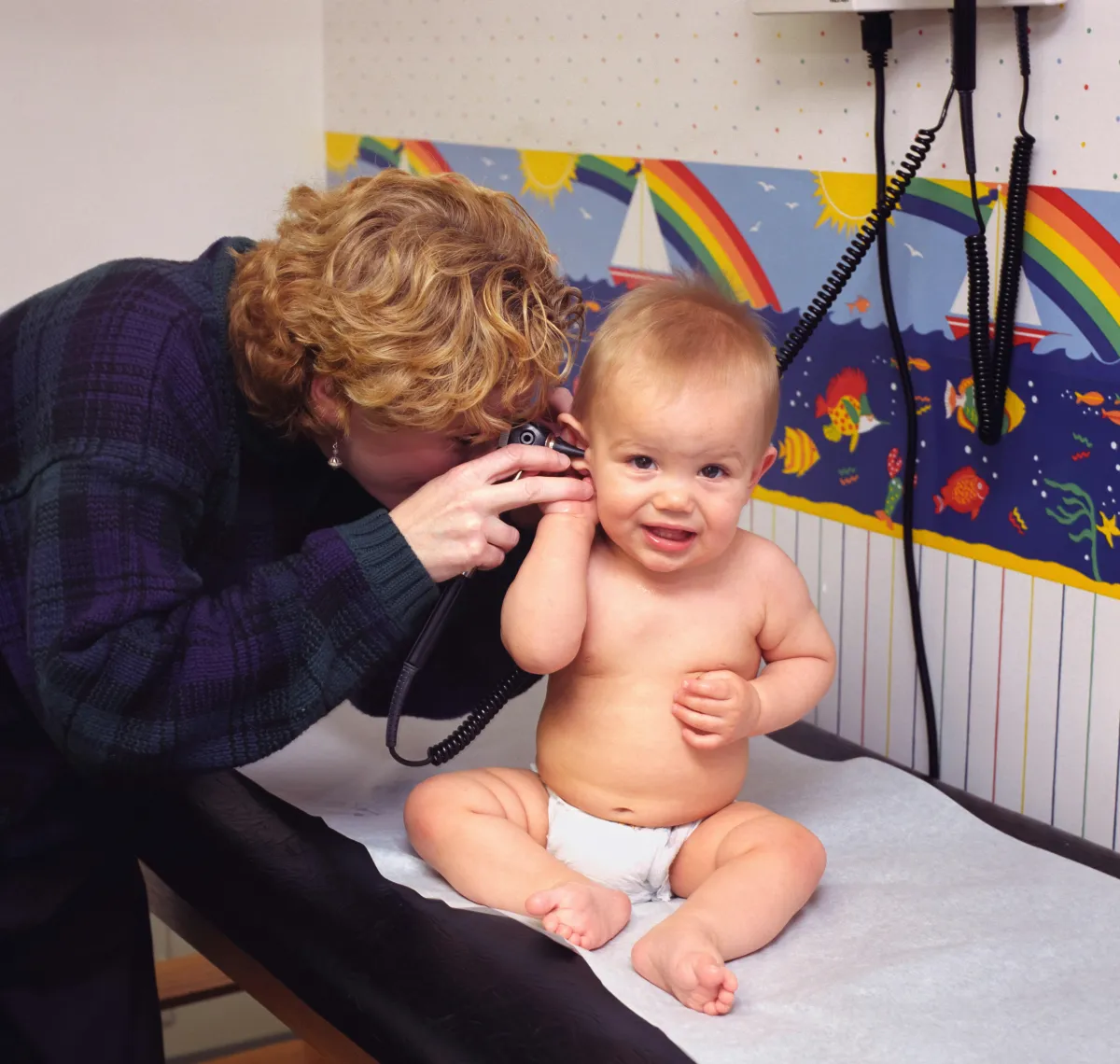 Pediatric provider checking a baby's ear with an otoscope during an ear infection exam Pediatric provider checking a baby's ear with an otoscope during an ear infection exam