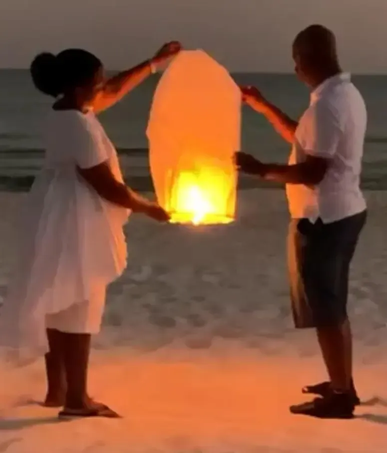 Family members releasing a sky lantern on the beach as a symbol of healing, hope, faith, and finding purpose through loss.
