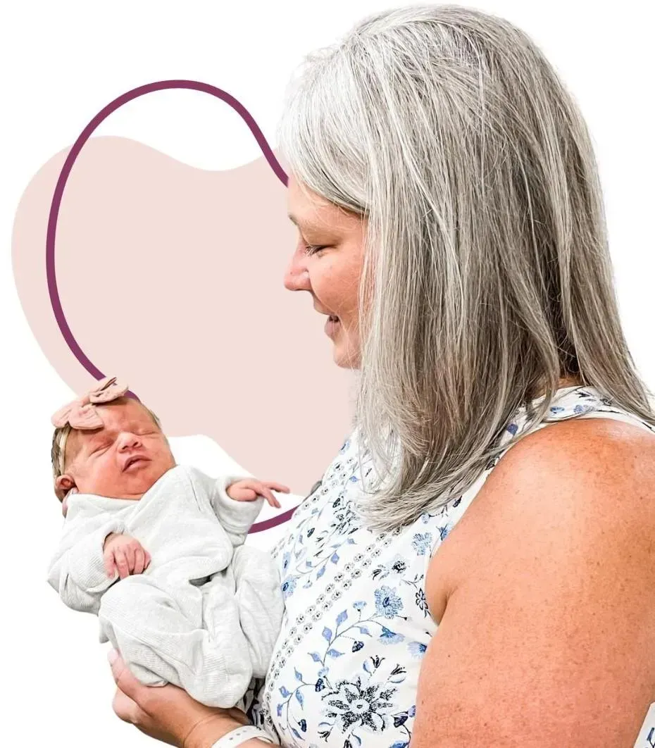 Dr Dawn adjusting a small baby in a gray outfit against a soft pastel background, radiating warmth and affection.