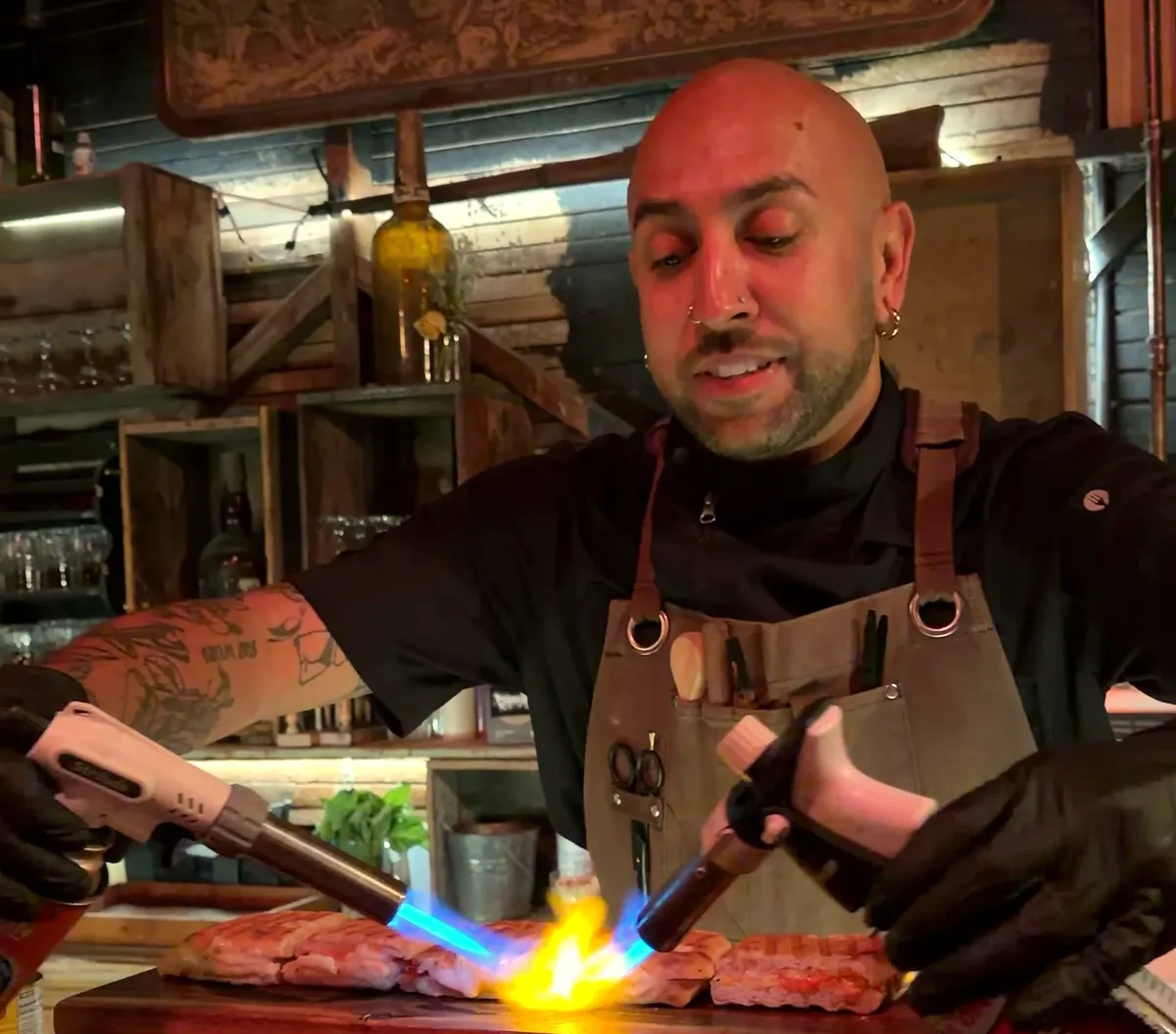 A chef torching omakase with two flames