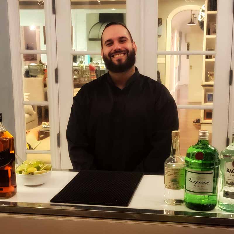 Smiling bartender standing behind a bar.