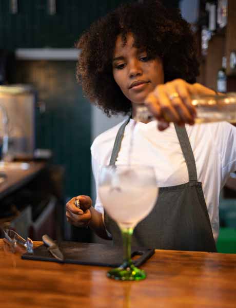 Bartender pouring a drink into a glass.