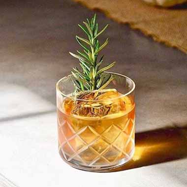 Cocktail in a glass with a rosemary garnish.