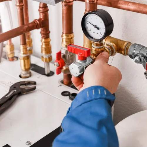 A plumber adjuts a pressure gauge in a newly isntalled waterline in a Spring Hill, KS utility room.