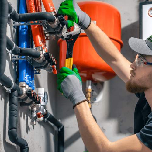 A plumber adjusts the tightness on pipe fittings in a Spring Hill, KS commercial building