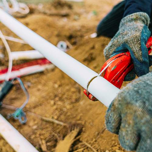 a plumber trims a pvc pipe during a water line replacement in spring hill, ks