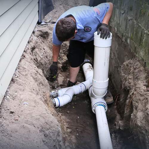 a plumber feeding a drain pipe into a septic tank that needs to be replaced in spring hill, ks