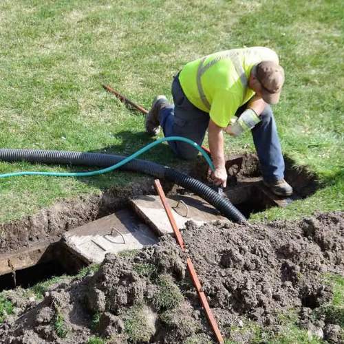 a plumber feeding a drain pipe into a septic tank that needs to be replaced in spring hill, ks