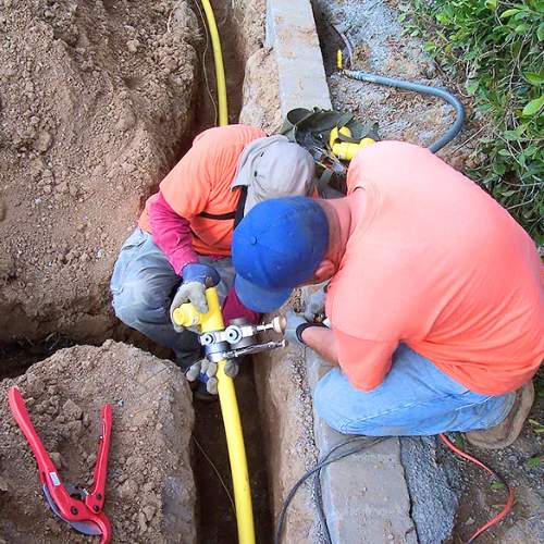 two plumbers installing a new gas line in a trench in a front yard in spring hill, ks