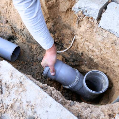 a plumber is replacing a sewer line in a trench in Gardner, KS