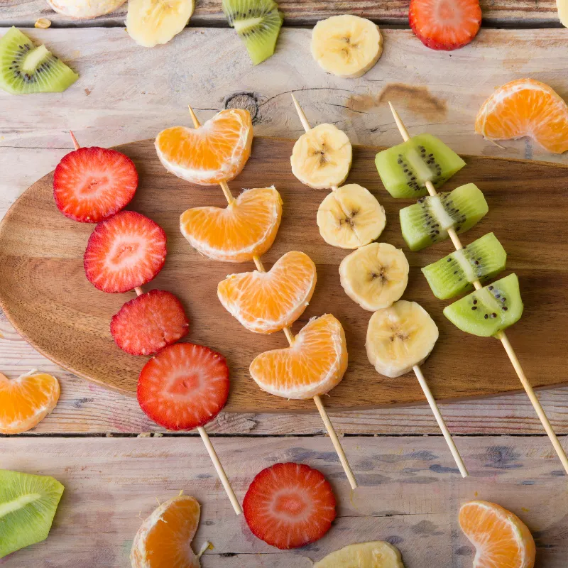 Fresh fruit skewers with strawberries, mandarin orange, banana, and kiwi, representing colorful nourishment and balanced living for moms