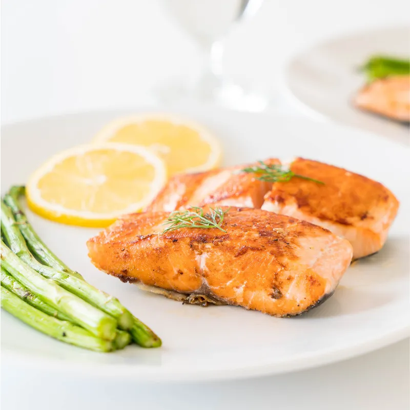 Plate of salmon with asparagus and lemon, symbolizing balanced, nourishing offerings in signature coaching programs