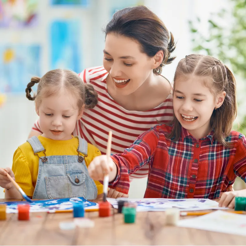Happy mom and daughters painting together, showing creativity, connection, and joy in motherhood