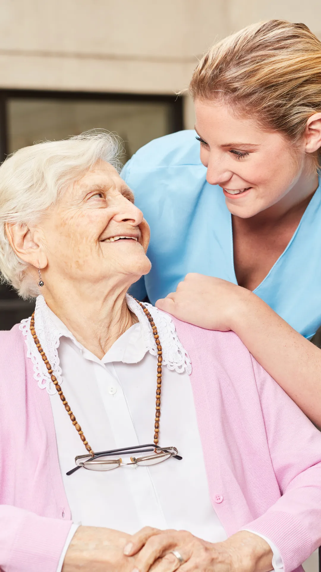 Smiling elderly woman receiving emotional support from live-in carer at home