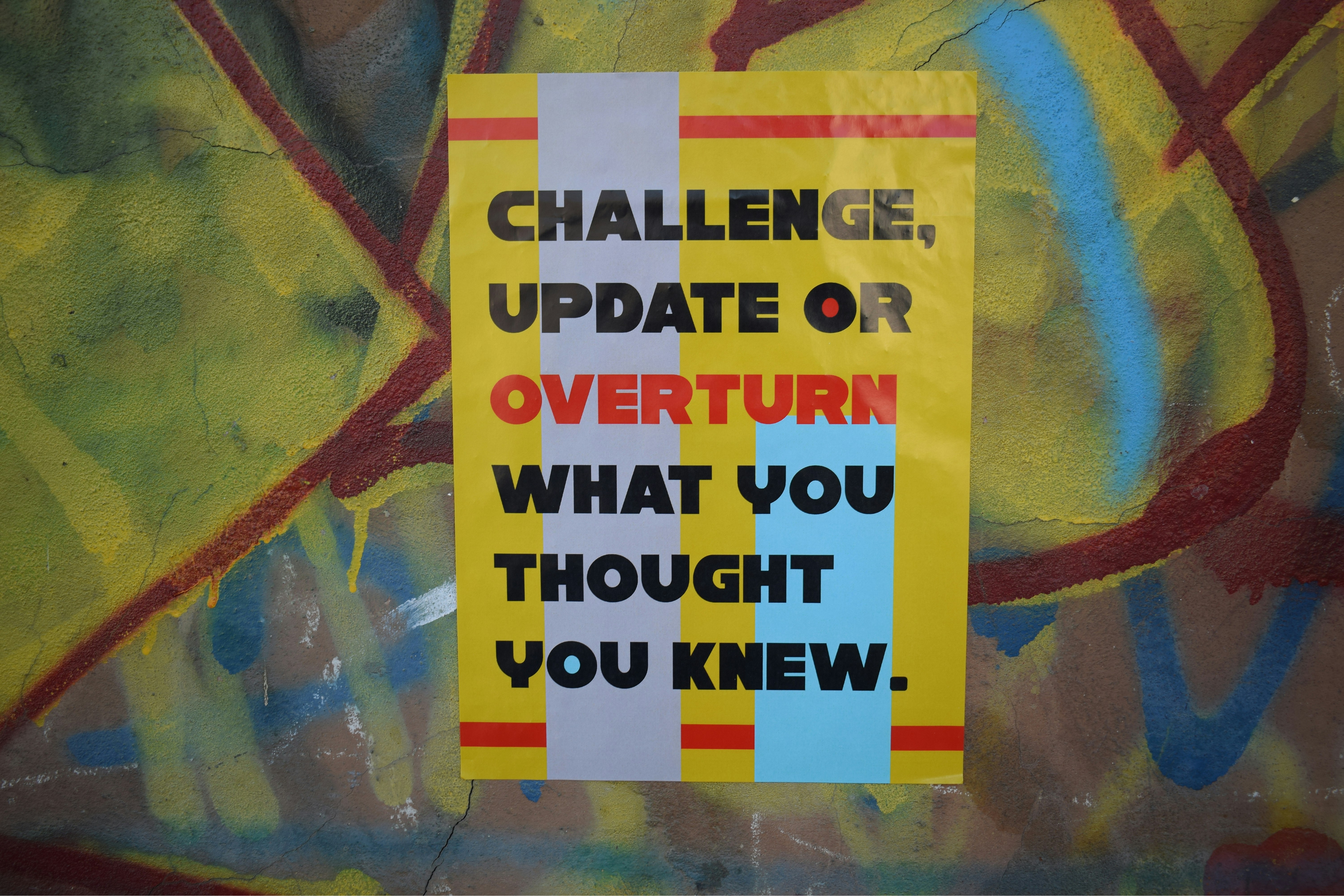 Yellow banner with writing saying: challenge, update, overturn what you thought you knew