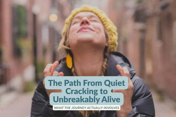 A woman in a yellow knit hat and dark winter coat tilts her face up toward the sky with eyes closed, hands raised in a moment of relief, on a brick-lined street. Text overlay reads: The Path From Quiet Cracking to Unbreakably Alive — What the Journey Actually Involves.