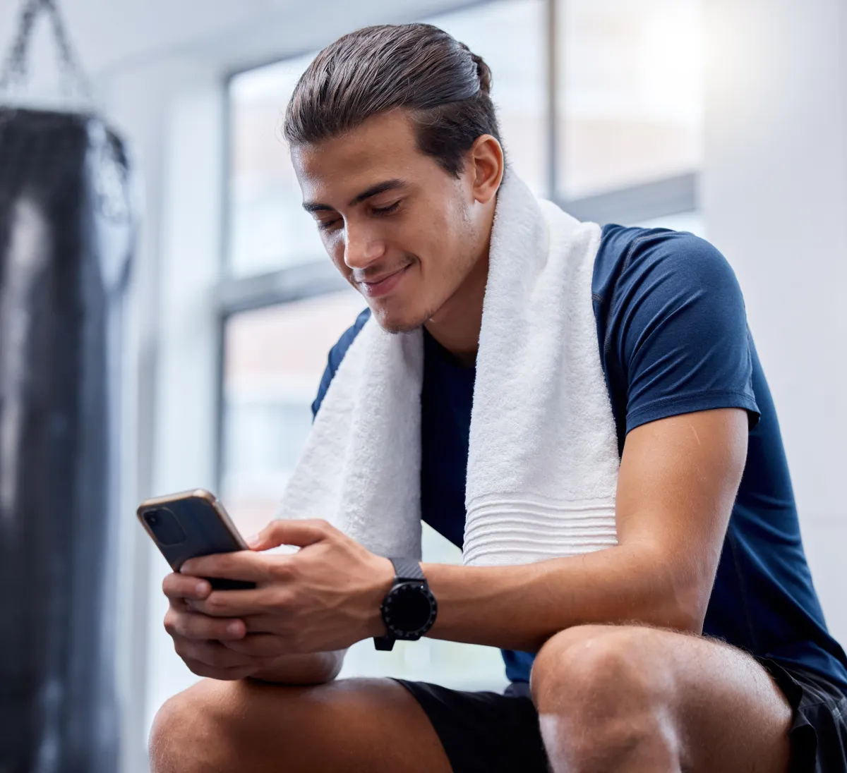 Sporty guy using his phone in the gym to create his PDF product after a workout