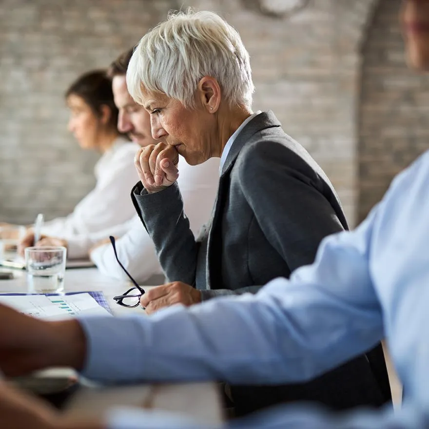 A woman thinks about data during a business assessment meeting.