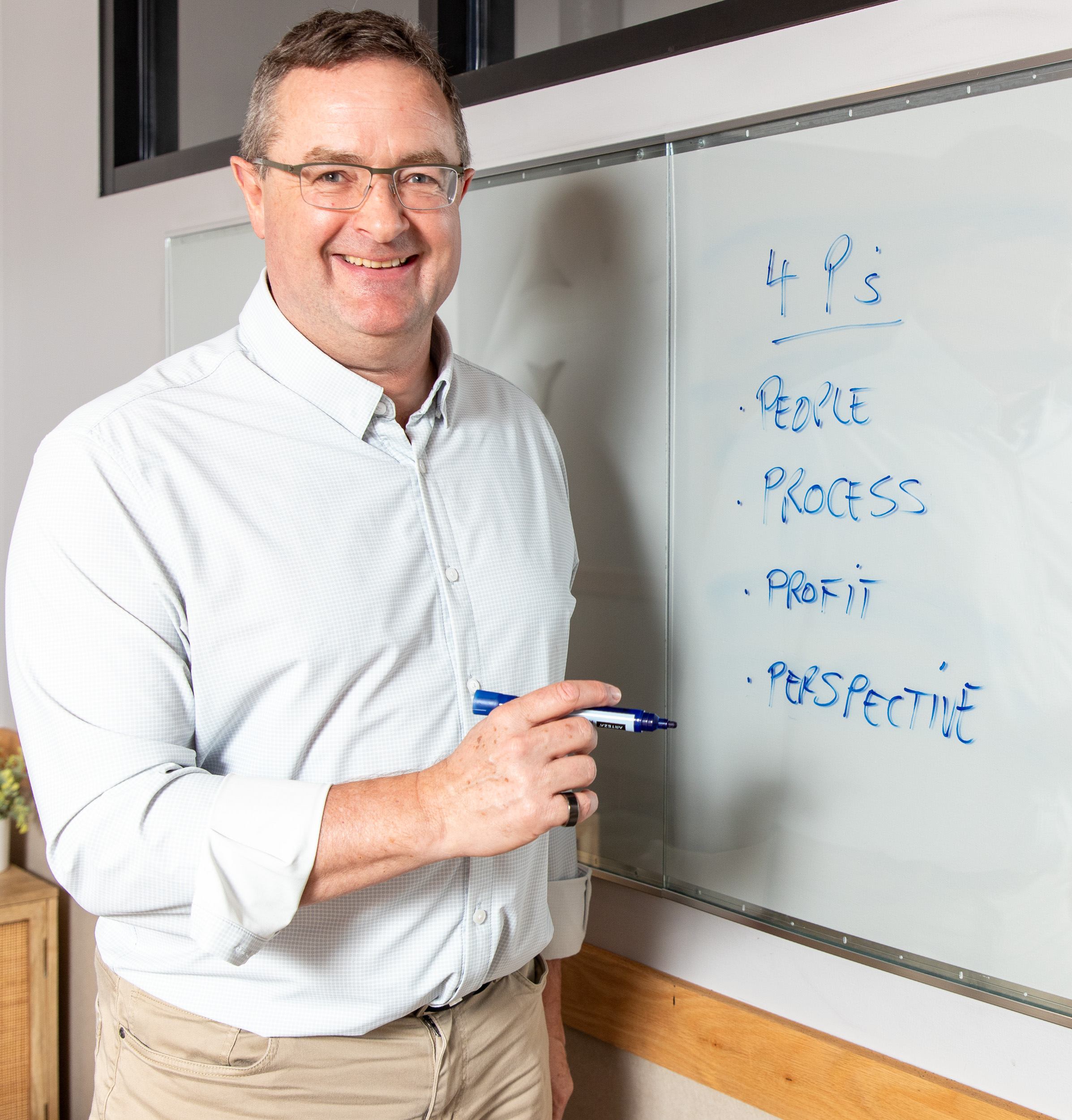 Paul standing at a whiteboard during a 4P Flight Plan workshop, sketching process improvements for a growing team.
