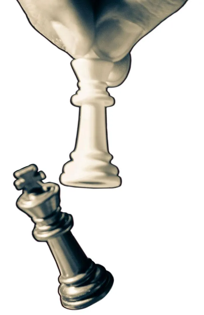 Hand with 2 chess pieces, the queen knocking over the king