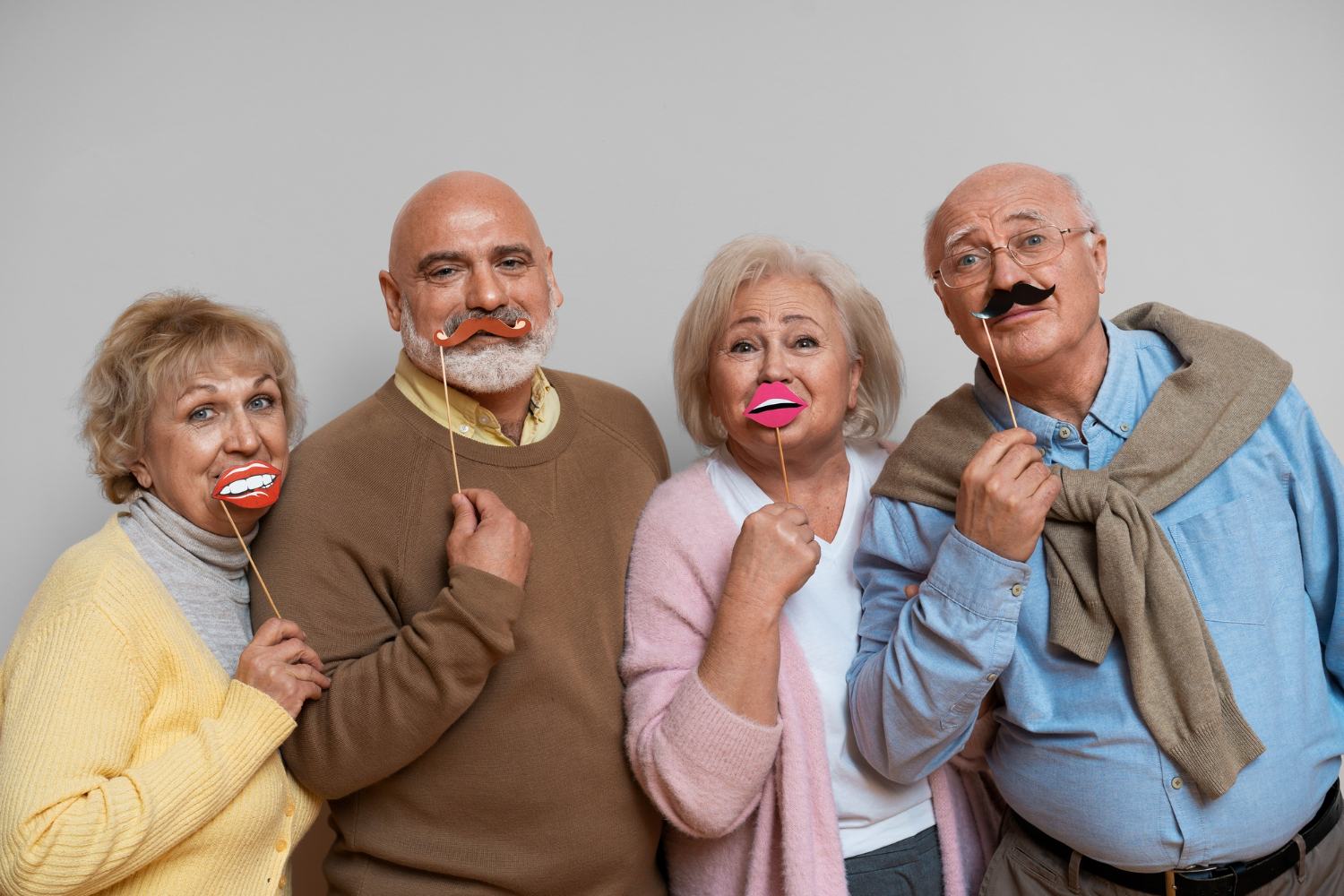 Silly seniors holding up fake mustaches and mouths on sticks.
