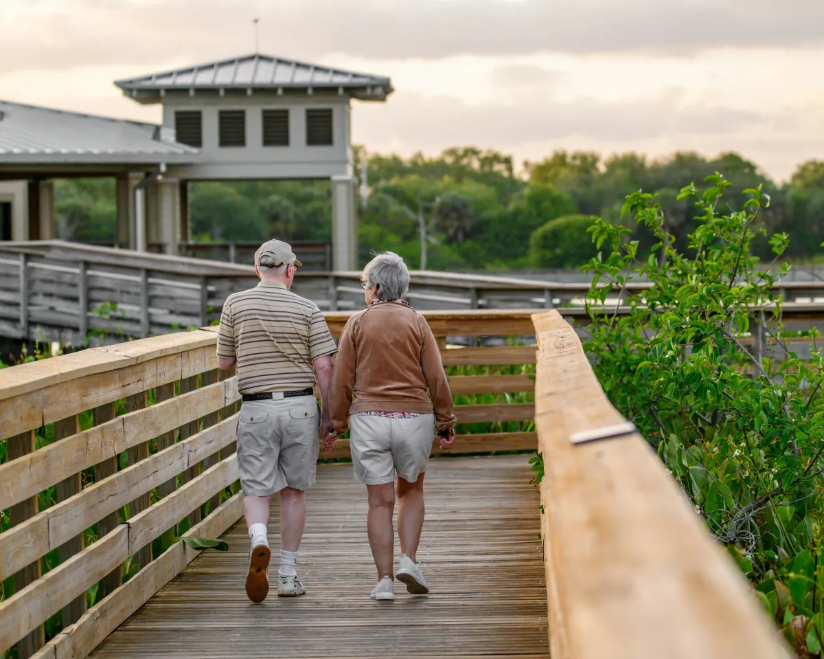 Two seniors staying active, walking on a boardwalk.