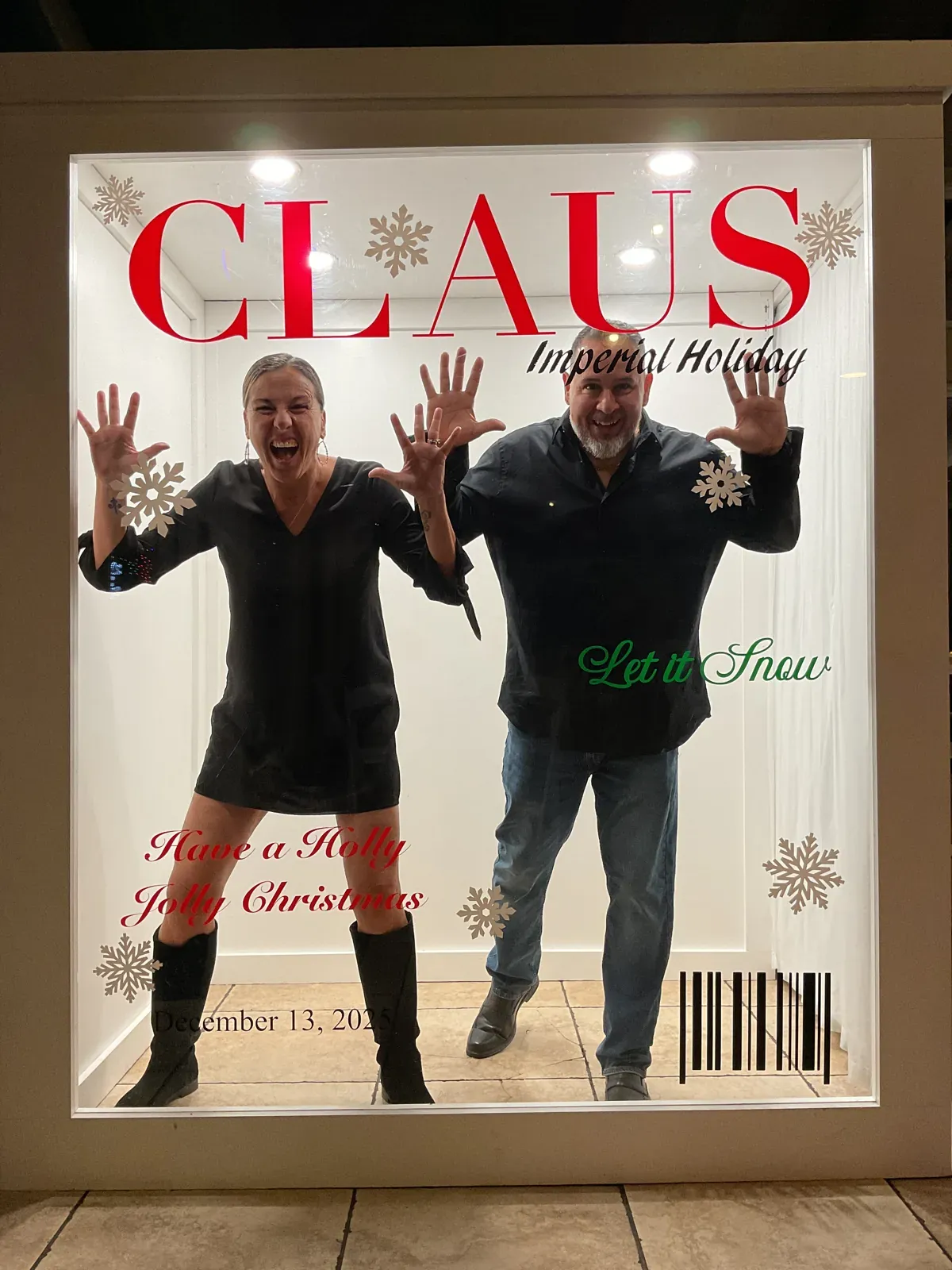 Two guests posing inside a Christmas magazine cover photo booth
