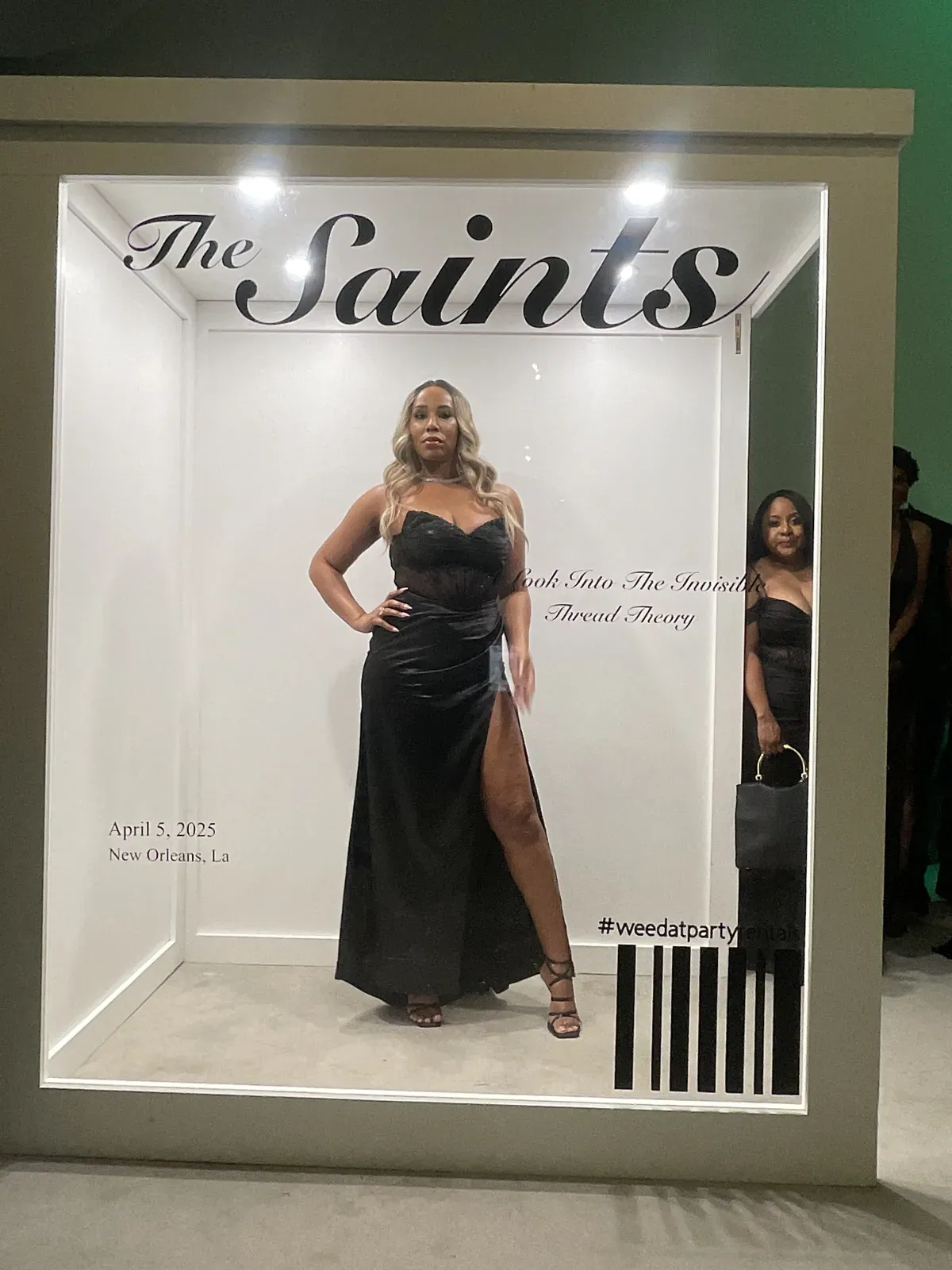 Guest in a black dress posing inside a Saints magazine cover photo booth