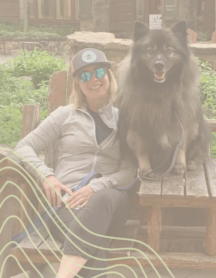 Kim Ribich, founder of Inner Wild Coaching, sitting outdoors with her dog Magnus