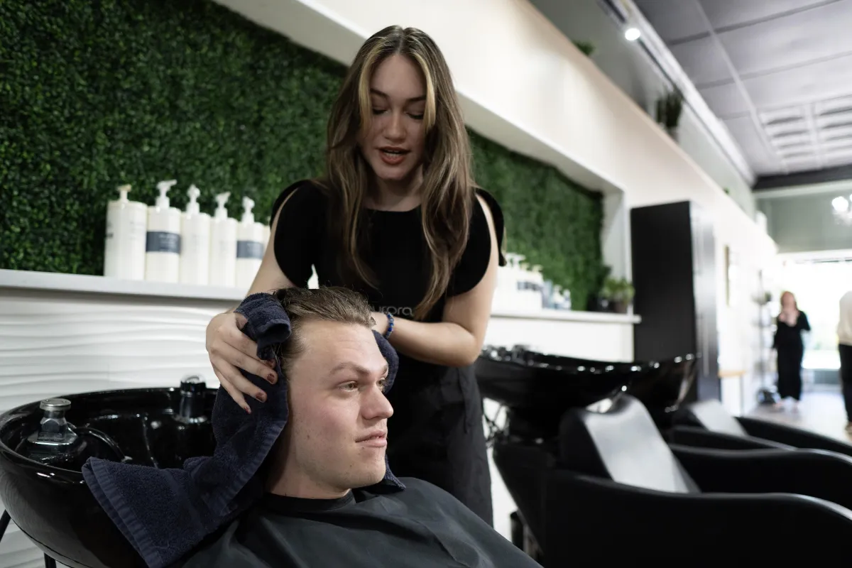 Avera hairs studio shampoo bowls with eufora products on the shelf with a green grass wall. 