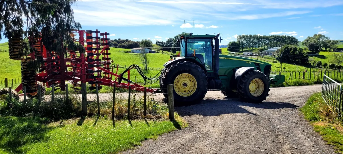 A&L Contracting NZ’s tractor driving down farm road with agricultural implement for soil work