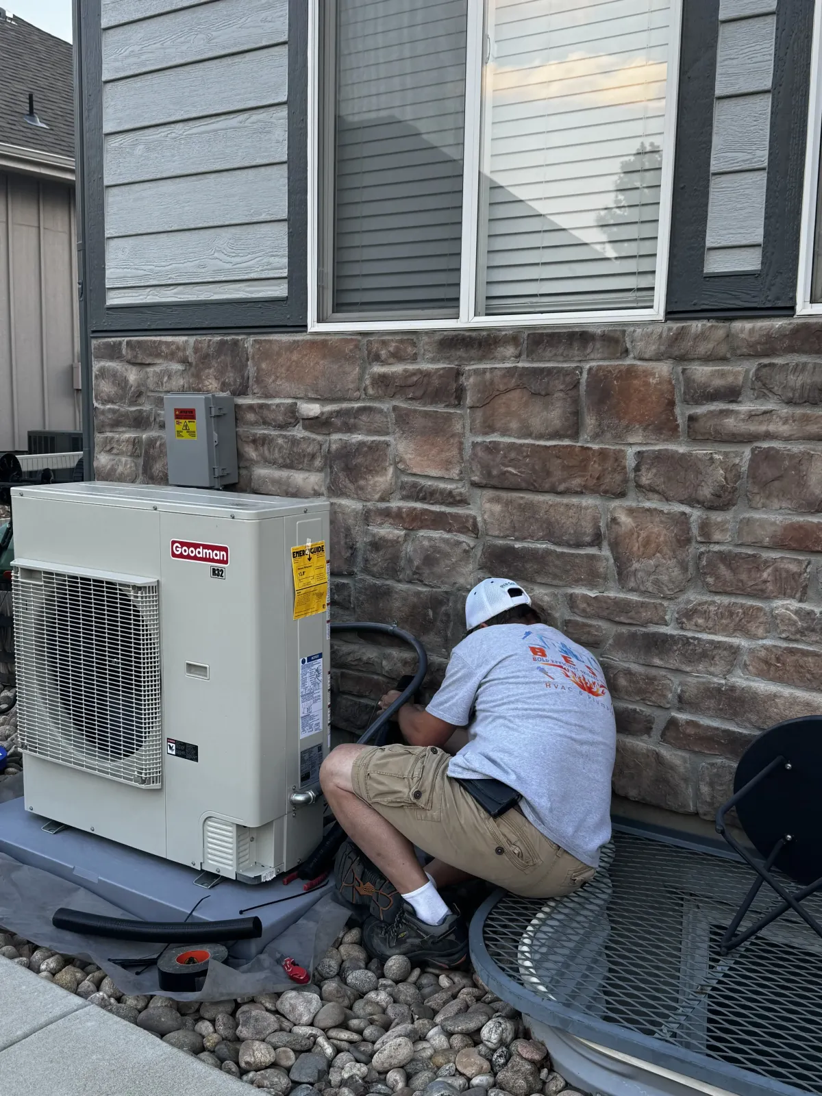 HVAC technician installing Goodman heat pump for Topeka home energy-efficient upgrades.